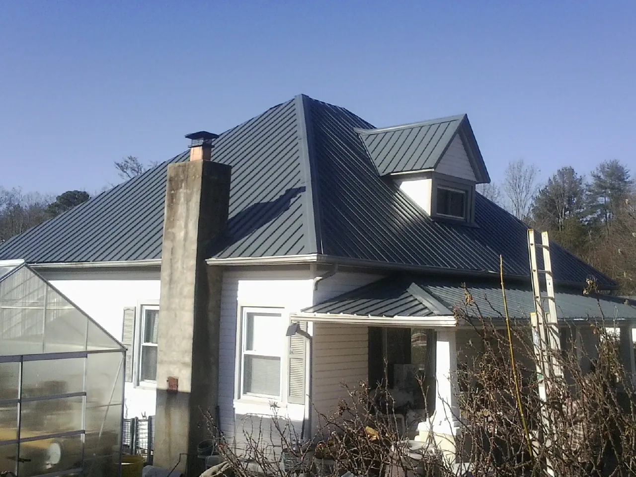 Dark blue standing seam metal roof on a white farmhouse with dormer — Slate & Tile Roof Repair by Roofing Brothers in Marblemount