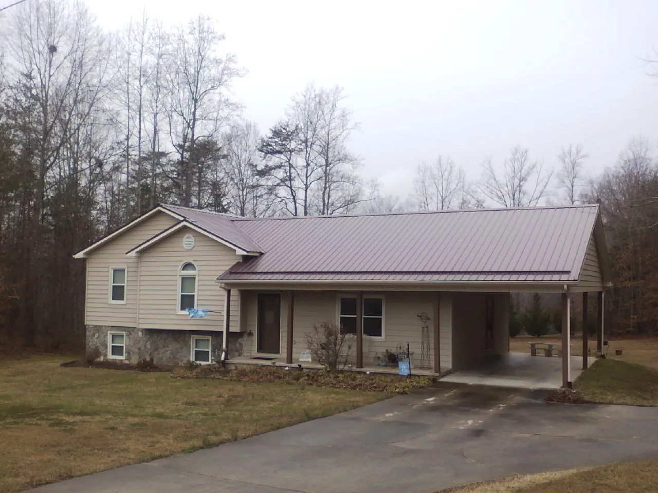 Burgundy metal roof on a tan split level home with an attached carport in Marblemount