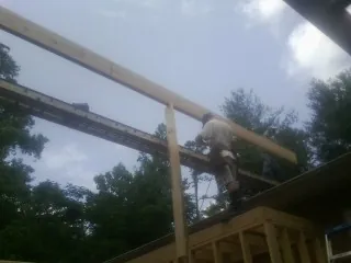 Carpenter setting a ridge beam over a new addition frame — Ice Dam Removal by Roofing Brothers in Marblemount