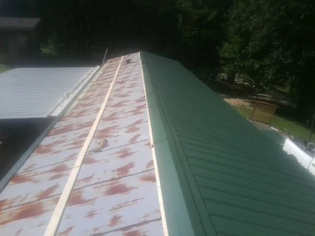 Old rusted panels beside newly installed green metal roofing — Wind Damage Roof Repair by Roofing Brothers in Marblemount