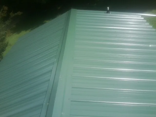 New green metal panels meeting at the ridge of a roof — Flat Roof Repair work by our crew in Marblemount