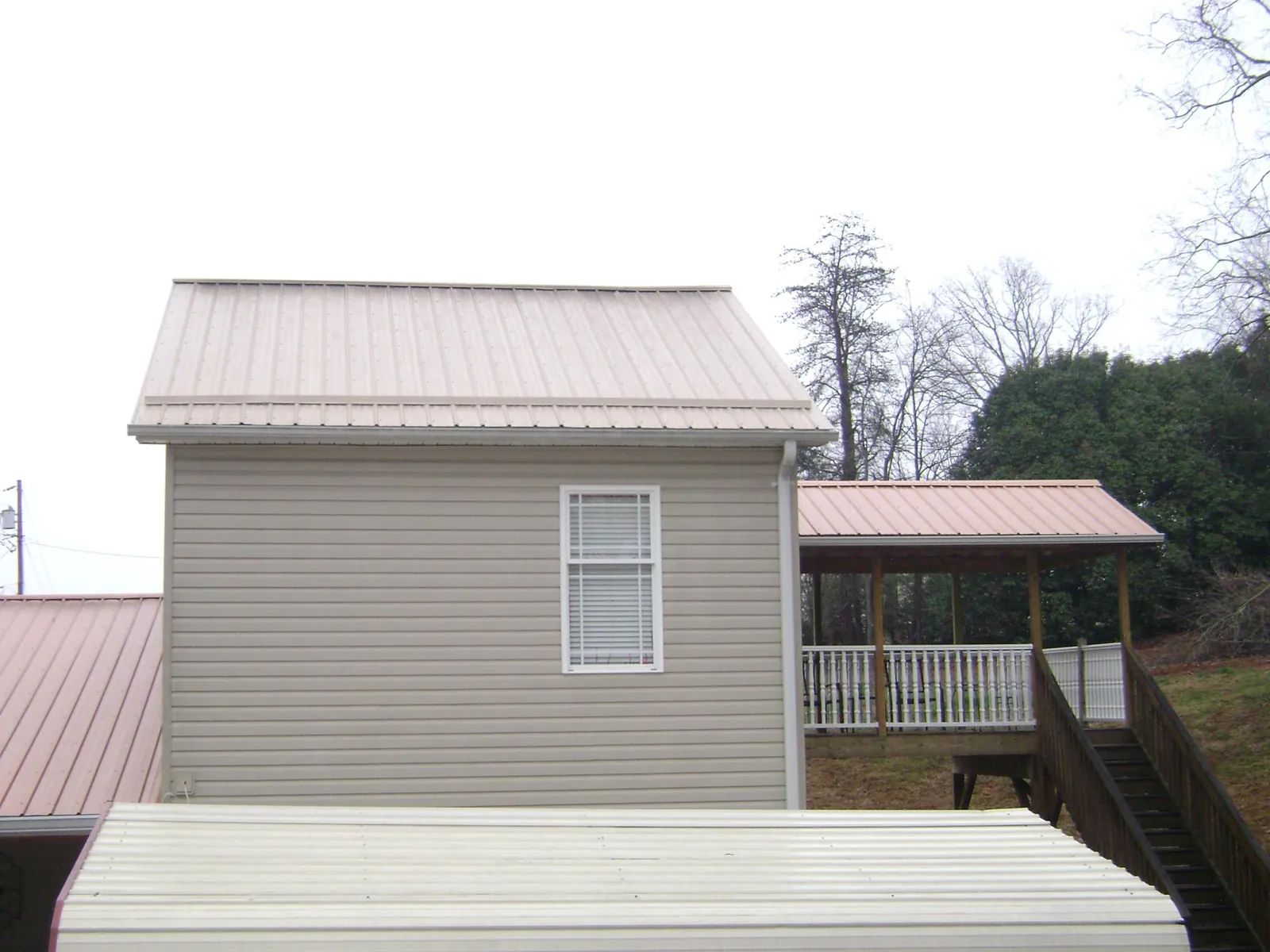 Tan metal roofs on a two story addition and attached porch, from a Roof Replacement job in Marblemount