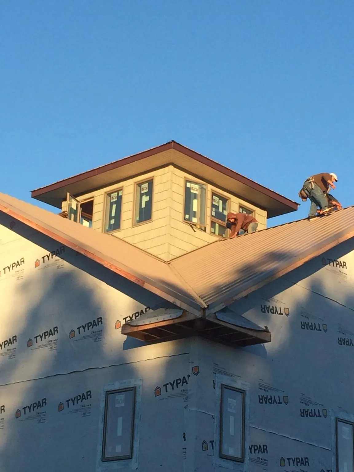 Roofers working around a rooftop cupola on a new metal roof at sunset — Roof Waterproofing in Marblemount by Roofing Brothers